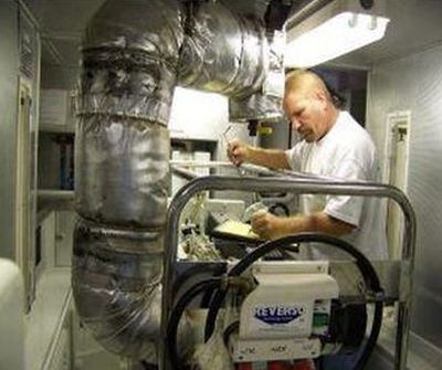 A man working in an industrial kitchen with pipes.