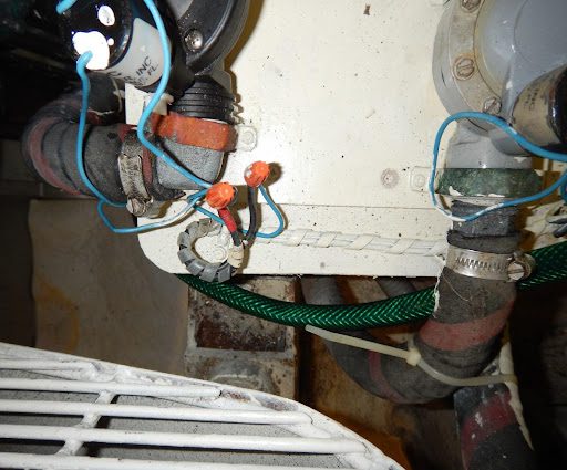 A close up of the pipes and wires on a water heater.